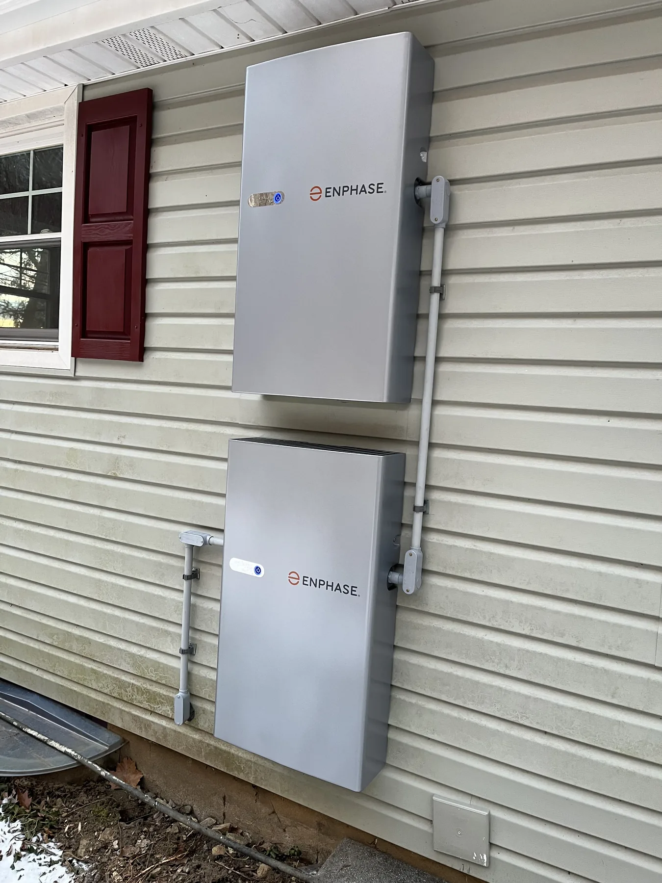 Two stacked Enphase battery cabinets and conduit on a home's exterior wall