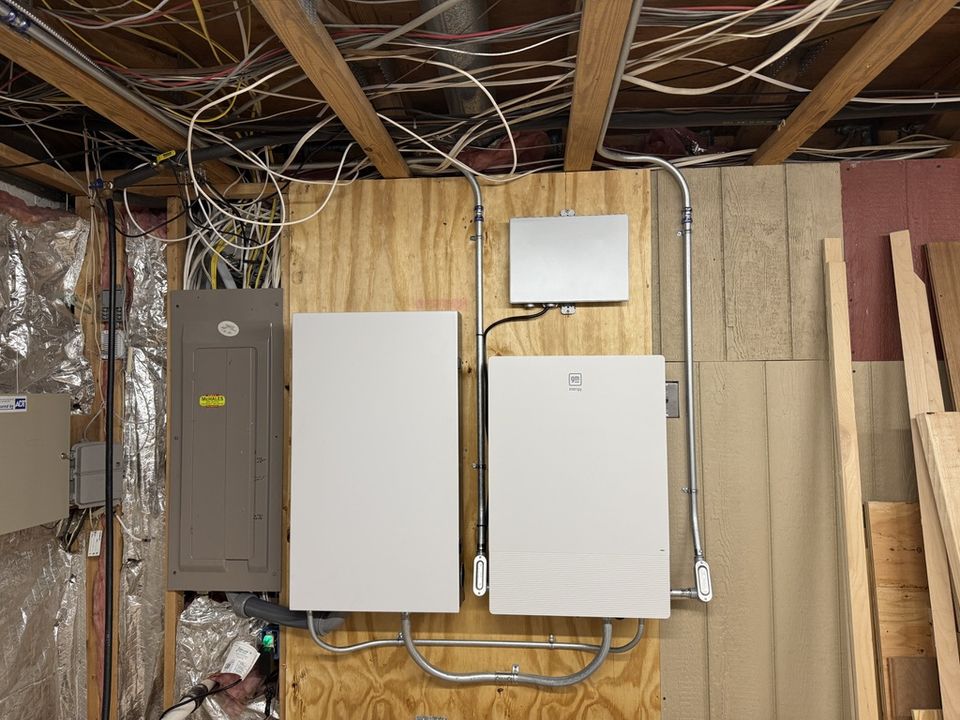 GM Energy V2H equipment installed beside a residential electrical panel with surface-mounted conduit